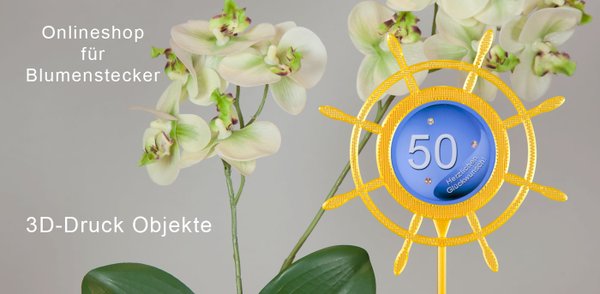 Frontale Aufnahme von einer Orchideenblüte mit einem 3D-gedruckten Blumenstecker-der goldfarbene Blumenstecker hat die Form eines Steuerrads und ist mit einem Bild "50 und herzlichen Glückwunsch " versehen