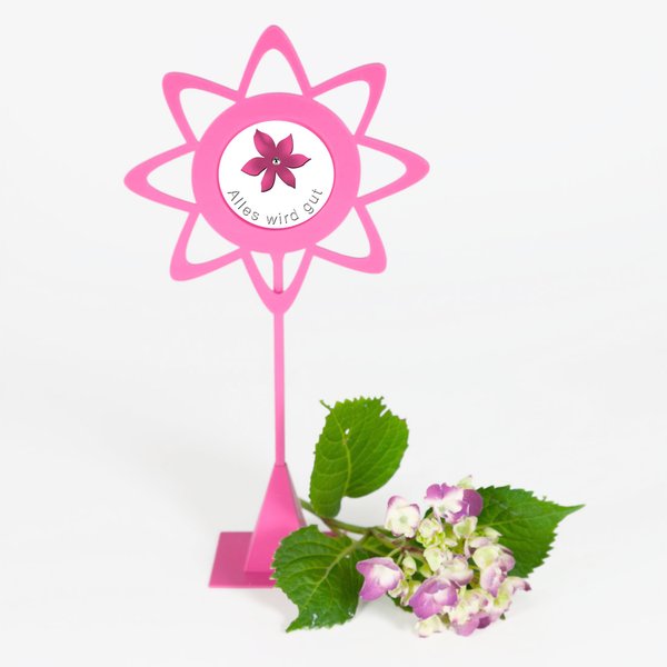 Vorderansicht eines Blumenstecker-Zierrings in Blütenform - Der Blumenstecker ist pinkfarben und mit einem Standfuß versehen-dekoriert mit einer rosafarbenen Hortensienblüte